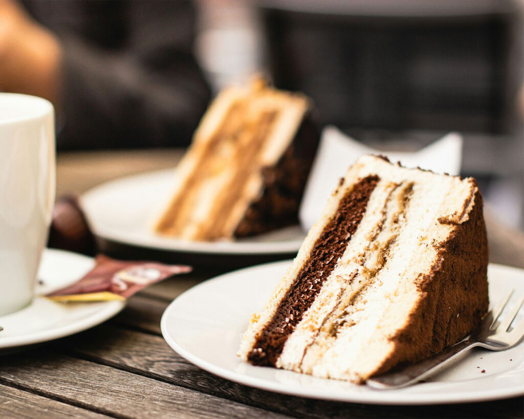 A single slice of moist chocolate cake on a white plate, topped with glossy chocolate ganache, highlighting its soft texture and deep cocoa colour.