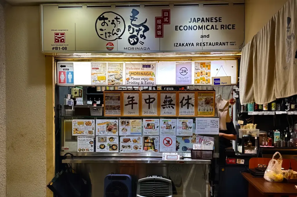 Storefront of Morinaga Izakaya Restaurant at Midpoint Orchard, Singapore. Signage displays Japanese economical rice and opening hours. Authentic casual dining spot on Orchard Road for locals.