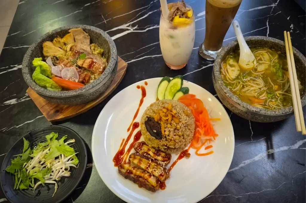 Vietnamese vegetarian dishes at Moon Chay Singapore including noodle soup, rice set, grilled plant-based items, and drinks on a marble table