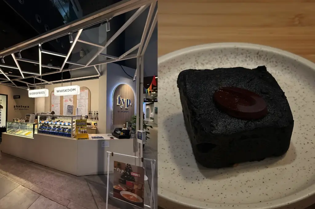A side-by-side split composition captures a modern food stall storefront and a close-up of a dessert offering, representing the file "3-The Five Best Dessert Shops in Orchard.webp". The left panel shows an eye-level view of a brightly lit indoor mall kiosk with an open white geometric scaffolding frame overhead, featuring signage for "BIGBIGFRIES", "WHISKDOM", and an arched lit logo reading "fyp. for you people." A glass display case reveals a row of baked goods, with a menu board and order counter visible under sleek track lighting. The right panel shifts to a tight close-up shot of a dense, dark chocolate square brownie or pastry sitting on a speckled off-white ceramic plate, highlighted by a single smooth, oval piece of dark chocolate melting slightly on top against a soft wood-grain background.