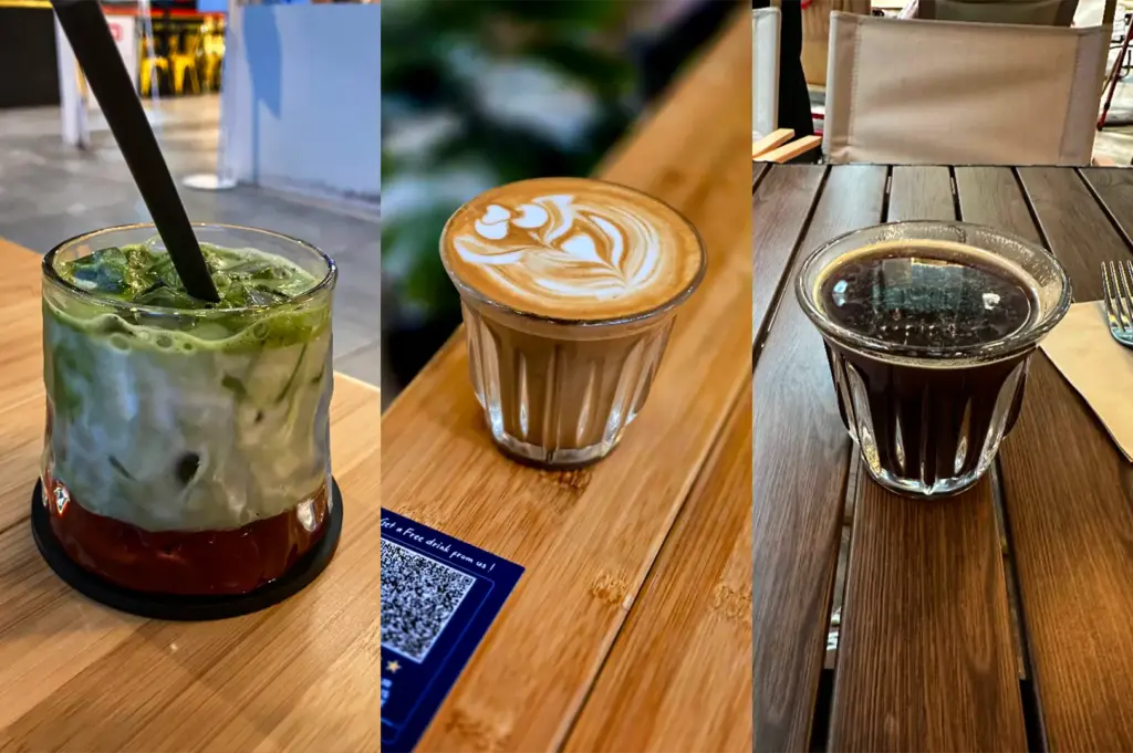 A three-panel split composition showcases a selection of carefully prepared beverages served in a cafe setting, representing the file "4-FYP Cafe Orchard Your Ultimate Destination.webp". The left panel features an iced matcha latte with visible swirls of green tea blending into fresh white milk, served with a black straw in a textured glass resting on a wooden tabletop. The middle panel shows a close-up, high-angle view of a hot latte in a small ribbed glass tumbler, showcasing delicate rosette and heart-shaped latte art etched into the rich crema. The right panel displays a clear glass cup filled with dark, rich black coffee or espresso sitting on a slatted wooden table next to a paper napkin and a fork, offering a simple and bold contrast to the milk-based beverages.